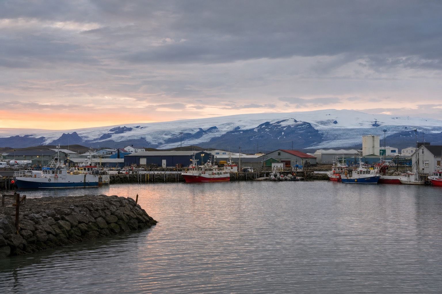 The small harbour town of Höfn in southeast Iceland with fishing boats and the Vatnajökull ice cap on the horizon at dusk