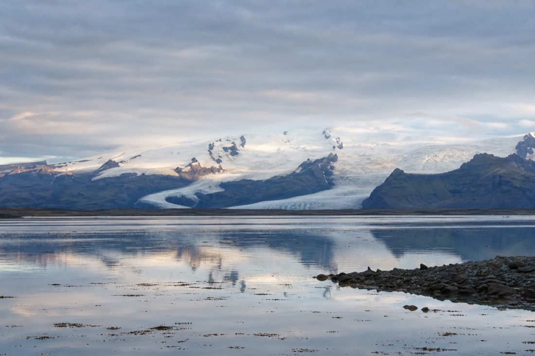 View from Höfn across still water toward the Vatnajökull ice cap and its glacier tongues under early morning light