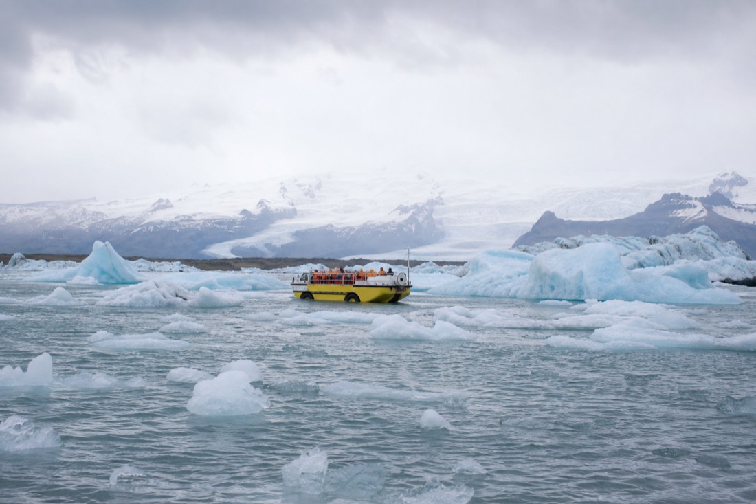 Amphibian boat carrying visitors among floating icebergs on Jökulsárlón glacier lagoon in summer