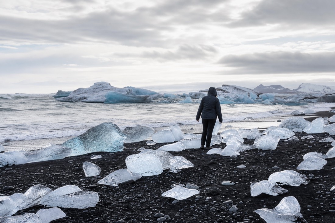 Visitors walking among glittering ice chunks on the black sand of Diamond Beach near Jökulsárlón in south-east Iceland