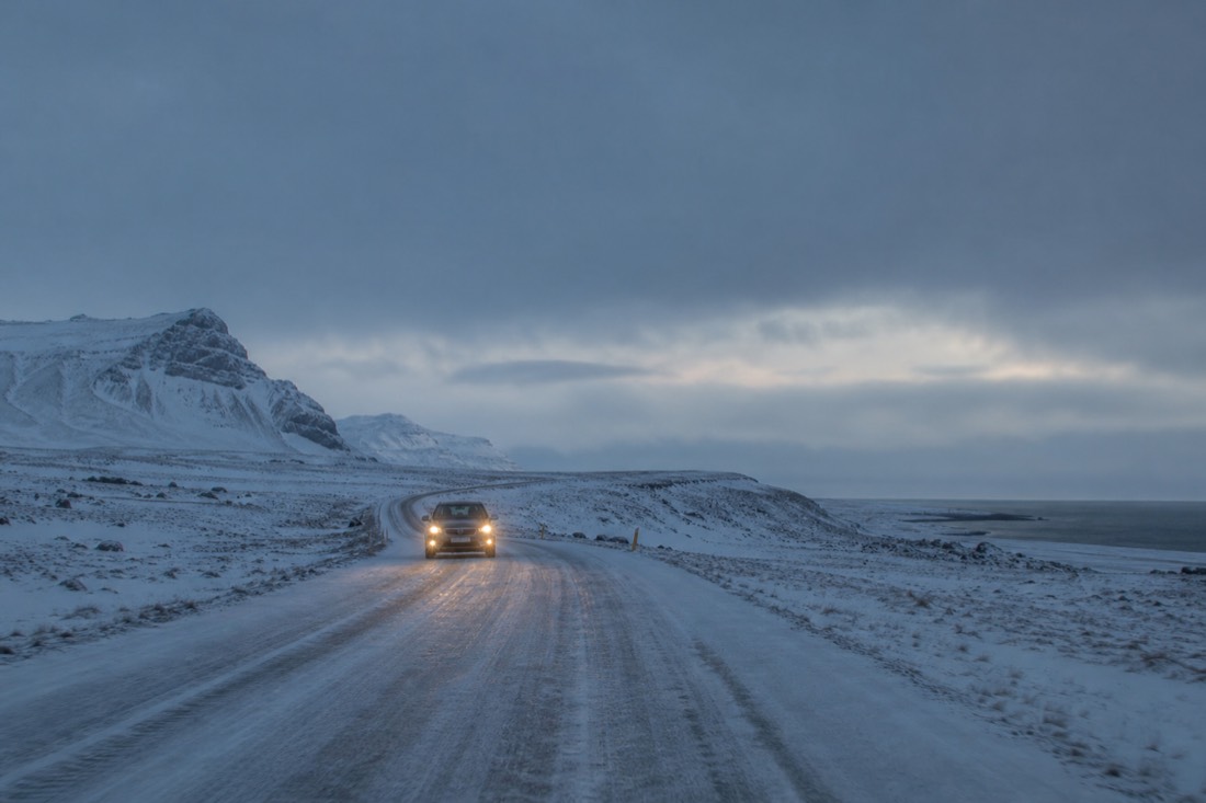 Route 1 under snow and low winter light on the drive to Jökulsárlón, headlights on in the short Icelandic daylight