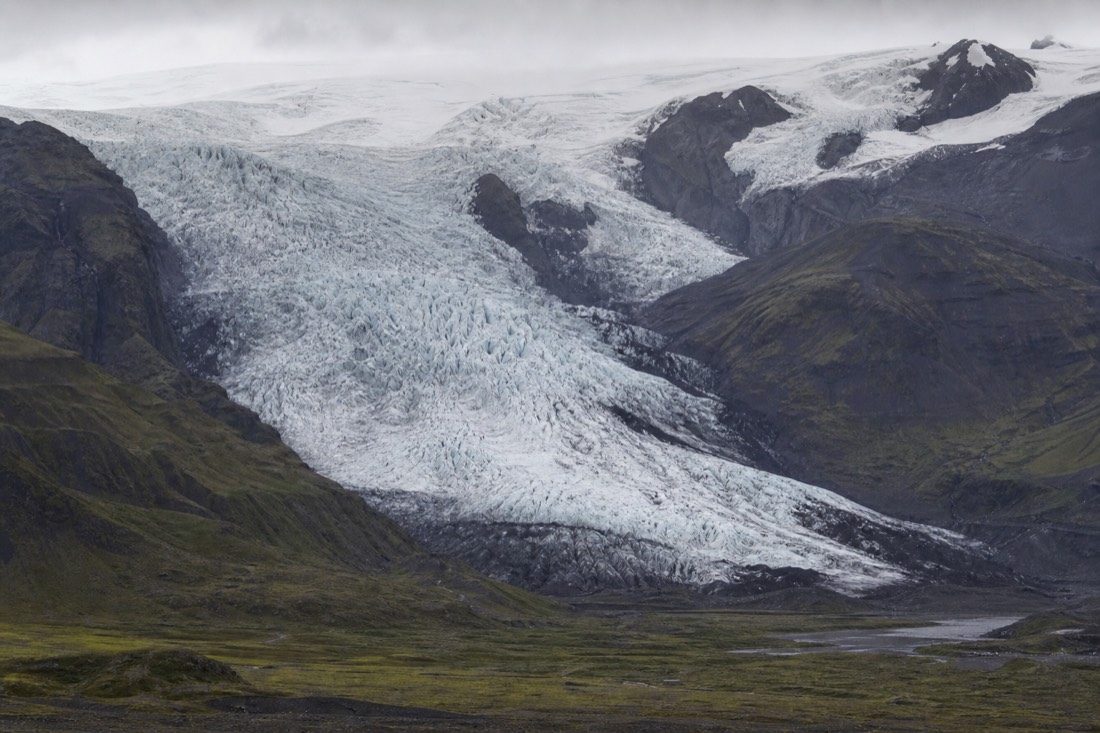 A glacier tongue spilling from the Vatnajökull ice cap down toward green and black terrain near Skaftafell